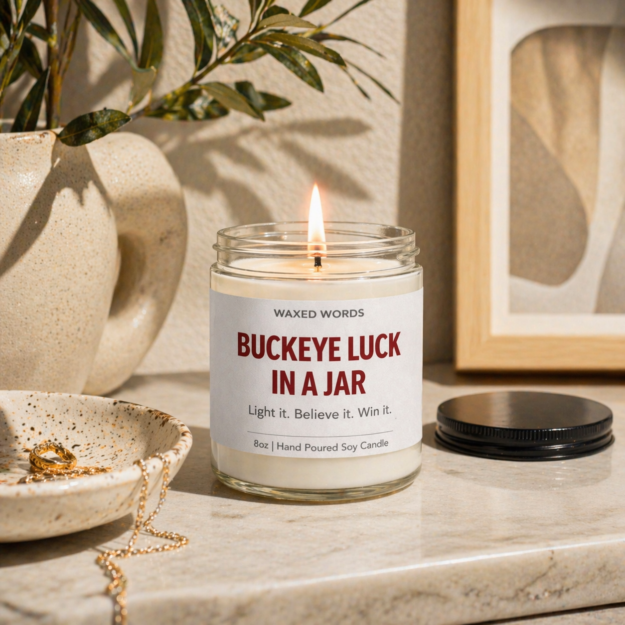 Waxed Words “Buckeye Luck in a Jar” candle on a wooden table with Ohio State jersey, cap, small football, and lucky charm items arranged before a game.