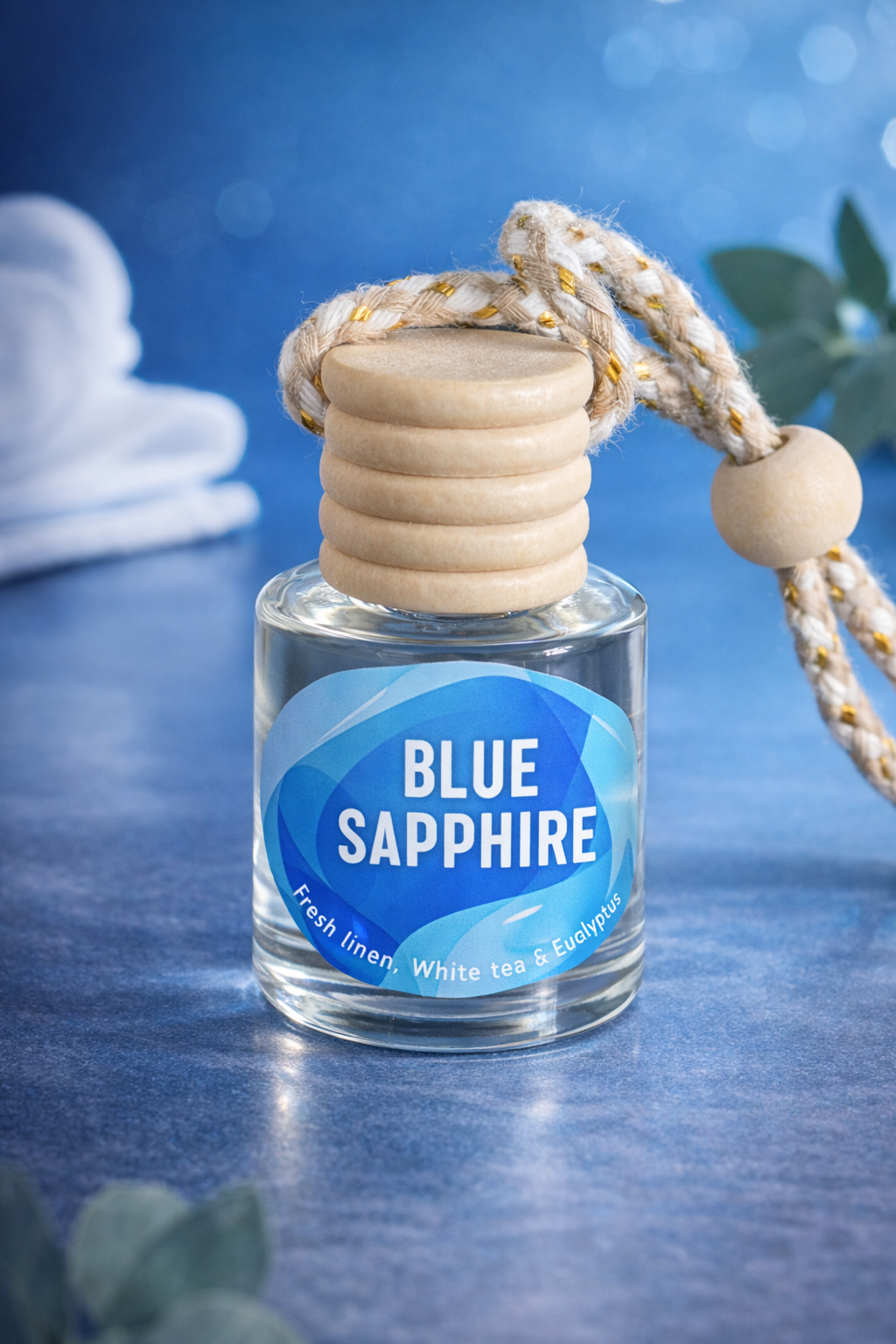 Blue Sapphire hanging car diffuser with glass bottle, wooden cap, and braided rope on blue background